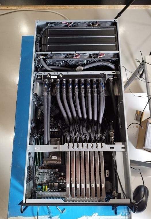 An open server platform seen from above: manifold, GPU block lines, radiator and fans