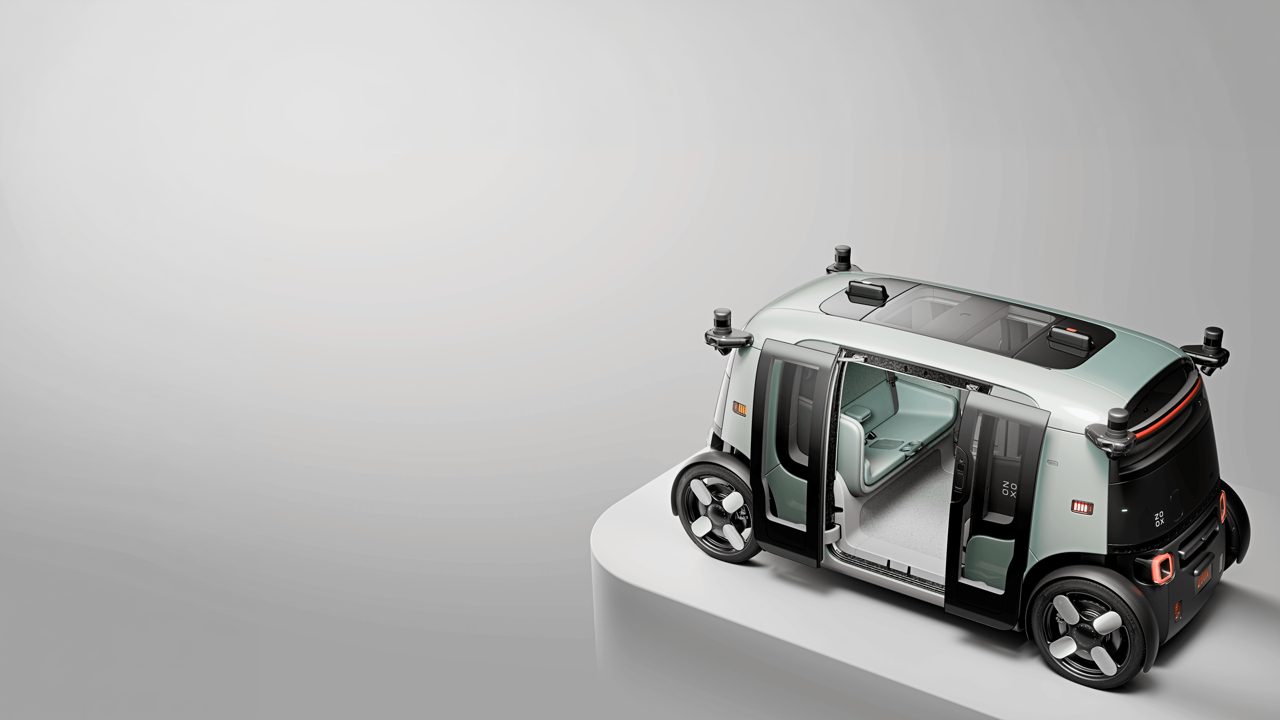 Zoox robotaxi with its doors open on a grey studio plinth